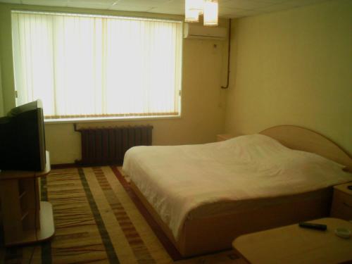 a bedroom with a bed and a television and a window at B&B Aktau НЕ ОТЕЛЬ in Aktau