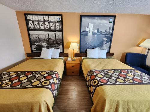 a hotel room with two beds and two windows at WestSpring Inn - Westlake Cleveland in Westlake