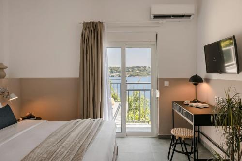 Habitación de hotel con cama, escritorio y balcón. en The Rock en Skíathos