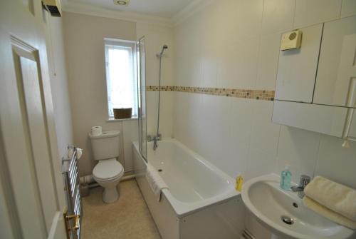 a bathroom with a toilet and a tub and a sink at Stylish Two-Bedroom Apartments in Windsor in Windsor