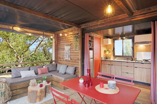a living room with a red table and a kitchen at Huttopia Arcachon in Arcachon