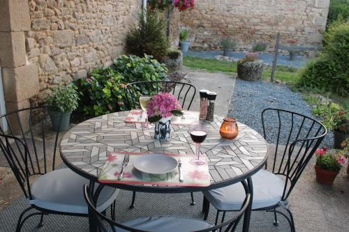 - une table avec des chaises et un verre de vin dans l'établissement Petite Ferme Embir, à Villegondoux