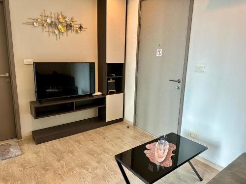 a living room with a table and a television at Best Location Condo with swimming pool, gym, sauna, washing mashine, Fast internet in Central of Pattaya in Pattaya