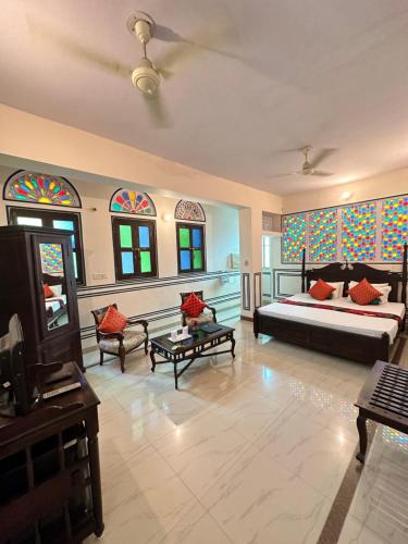 ein Wohnzimmer mit einem Bett, Stühlen und Buntglasfenstern in der Unterkunft Rawla Mrignayani Palace in Jaipur