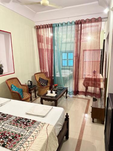 a bedroom with a bed and chairs and a window at Rawla Mrignayani Palace in Jaipur
