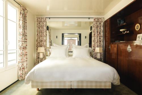 a bedroom with a large bed with white sheets and pillows at Les Suites Cinabre in Paris