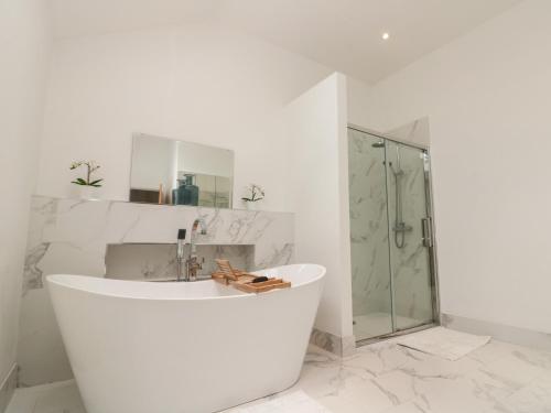 Bainton的住宿－Bailey house，白色的浴室设有浴缸和淋浴。
