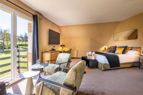 a hotel room with a bed and a large window at Le Manoir De La Poterie & Spa in Cricquebœuf