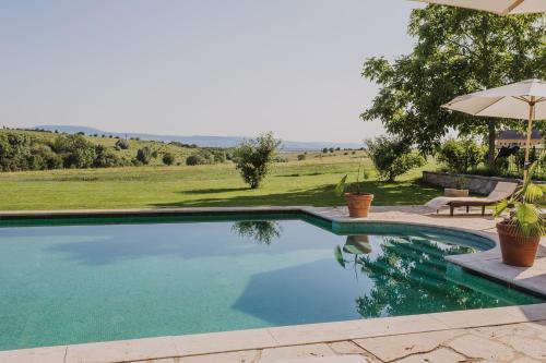 einen Pool mit einem Sonnenschirm und einem Tisch in der Unterkunft Hotel Château Bela in Belá