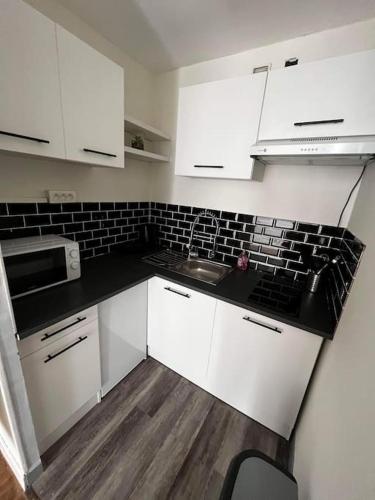 cocina con armarios blancos y encimera negra en Appartement T2 Chalons, en Châlons-en-Champagne