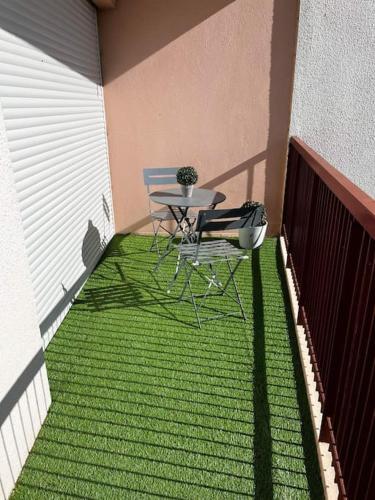 una mesa y una silla en un balcón con césped verde en Appartement T2 Chalons, en Châlons-en-Champagne