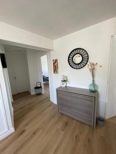 - un salon avec une table et une horloge murale dans l'établissement Les Embruns Valeriquais, à Saint-Valery-en-Caux