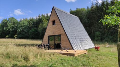 una piccola casa con tetto spiovente in un campo di La maison en A a Meix-devant-Virton