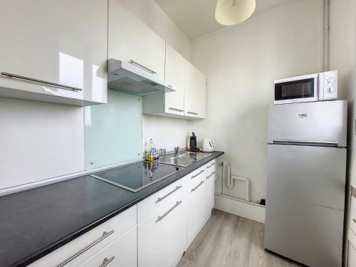 une cuisine avec des armoires blanches et un réfrigérateur blanc dans l'établissement IziLok Reims Centre Gare, à Reims