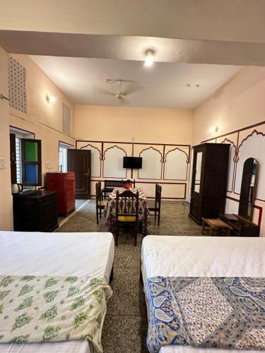 a room with two beds and a table and chairs at Rawla Mrignayani Palace in Jaipur