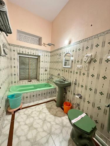 ein Badezimmer mit einer grünen Badewanne und einem Waschbecken in der Unterkunft Rawla Mrignayani Palace in Jaipur