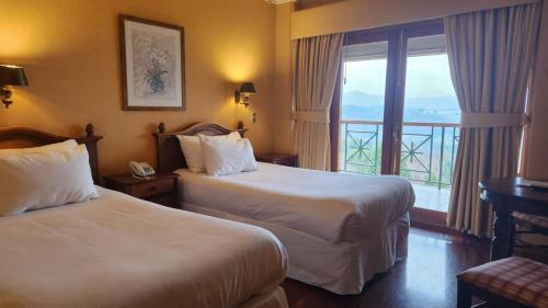 a hotel room with two beds and a balcony at Hotel y Cabañas Lago Ranco - Caja los Andes in Futrono