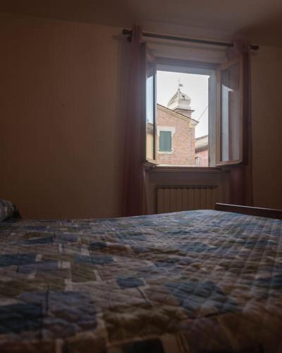 um quarto com uma cama e uma janela com um edifício em Nel tranquillo centro d'Isola em Isola di Fano