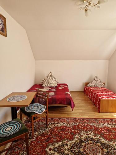Zimmer mit 2 Betten, einem Tisch und einem Teppich in der Unterkunft У ДЯДЬКА in Pilipets