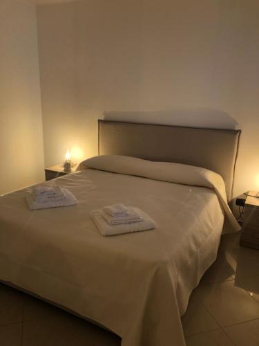 Una cama blanca con dos toallas encima. en Rosabella Casa Vacanze en Bari