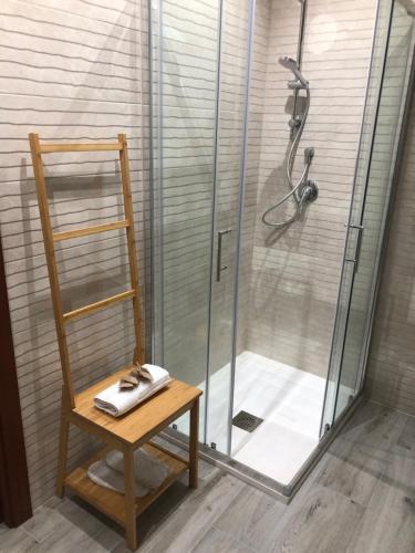 ducha con silla de madera y cabina de ducha de cristal en Rosabella Casa Vacanze en Bari