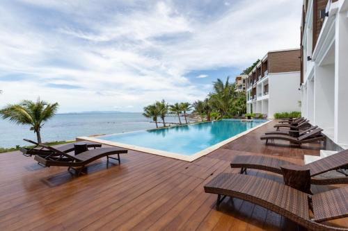 una piscina en la terraza de un hotel con sillas en X-Sea Khanom Harbor Bay Resort, en Khanom