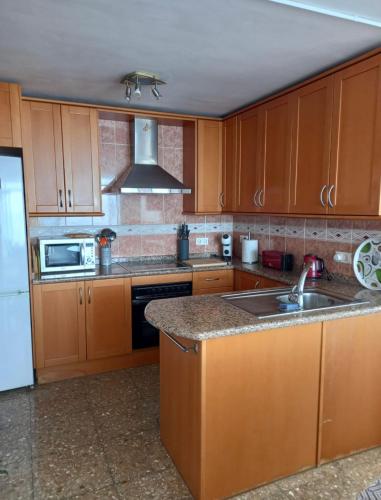 a kitchen with wooden cabinets and a sink and a microwave at Tahiti Dreams in El Campello