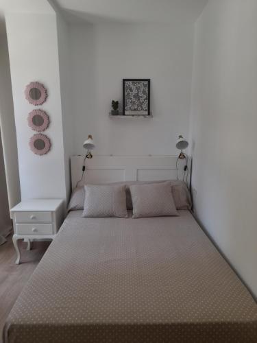 a bed in a white room with two lamps at Apartamento El Lago Cartagena Centro. in Cartagena