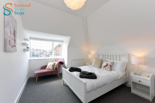 a bedroom with a white bed and a pink chair at Bella, two bedroom apartment close to the beach in Margate