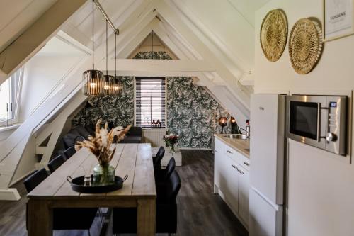 a kitchen and dining room with a dining table and a kitchen with a ceiling at Appartement ‘t-Yesenaertje in Yerseke
