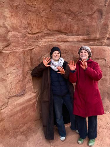 two women standing next to a rock wall at Desert's Soul Wadi Rum in Disah