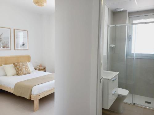 um quarto branco com uma cama e um chuveiro em ÁTICOS ROTA Punta Candor em Rota