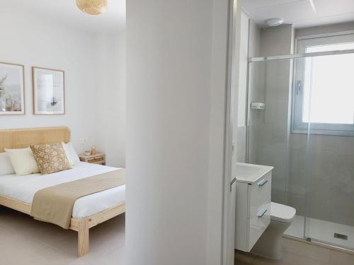a white bedroom with a bed and a shower at ÁTICOS ROTA Punta Candor in Rota