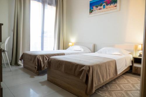 due letti in una stanza d'albergo con finestra di Sunset Villa a Hanioti