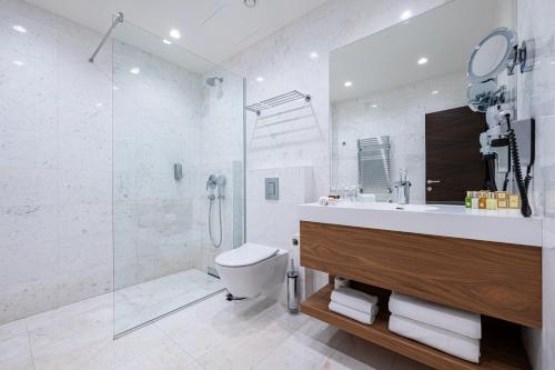 a bathroom with a sink and a shower and a toilet at Hotel California by Aycon in Sveti Stefan