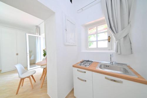 a white kitchen with a sink and a window at Villa Aida in Ischia