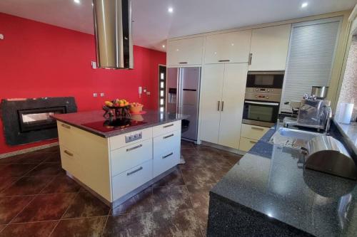 a kitchen with white cabinets and a red wall at Vila Azul in Amarante