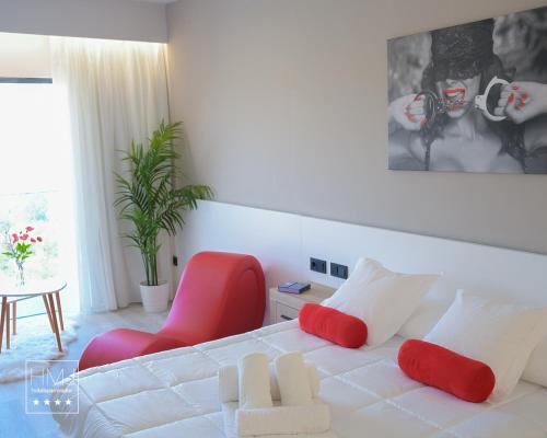 a bedroom with a white bed with red pillows and a red chair at Hotel Spa Mirador in Jorquera