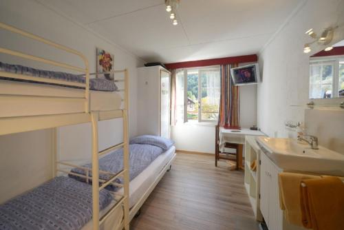 ein Schlafzimmer mit Etagenbetten und einem Waschbecken sowie ein Badezimmer in der Unterkunft Swiss Lodge Hotel Bernerhof in Wengen