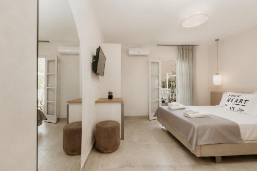 a white bedroom with a bed and a tv at TRINITY THE HOTEL in Ammouliani