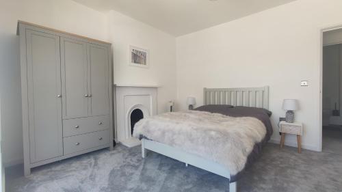 a white bedroom with a bed and a fireplace at Stunning One Bedroom Holiday Flat In Weymouth in Weymouth