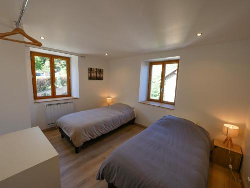 1 dormitorio con 2 camas y 2 ventanas en Gite de la Source-maison climatisée, 