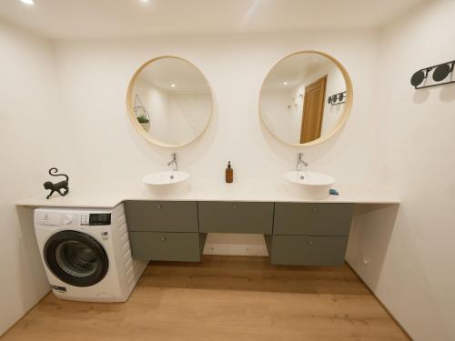een badkamer met 2 wastafels en 2 spiegels bij Gite de la Source-maison climatisée 