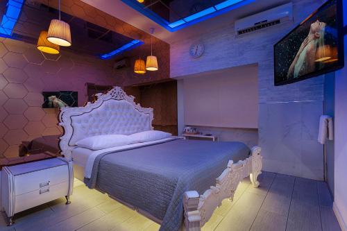 een slaapkamer met een wit bed en een televisie bij Metro Elegance Suites in Tel Binyamin