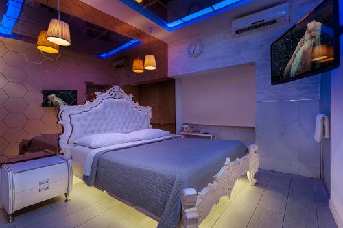 a bedroom with a white bed and a tv at Metro Elegance Suites in Tel Binyamin