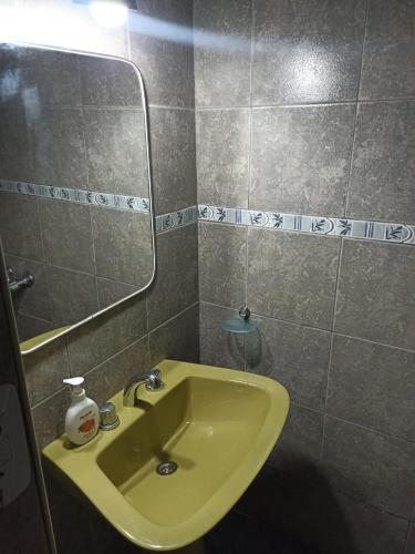 a bathroom with a yellow sink and a mirror at Complejo las Palmeras II in Mendoza