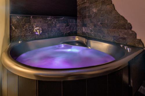 a blue tub in a bathroom with a brick wall at Metro Elegance Suites in Tel Binyamin