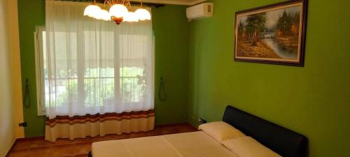 Dormitorio verde con cama y ventana en Vila Tahiri 2 en Golem
