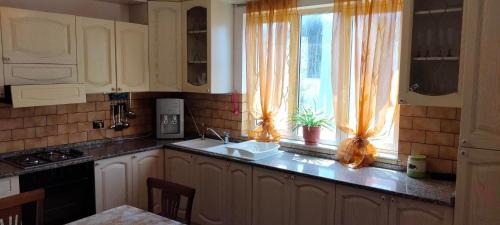 cocina con armarios blancos, fregadero y ventana en Vila Tahiri 2 en Golem