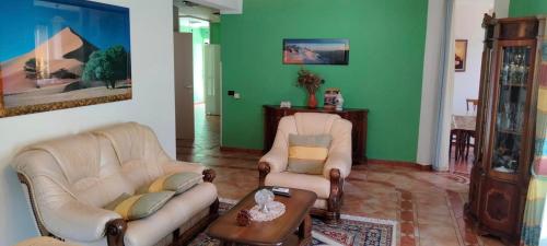 a living room with two furniture and a green wall at Vila Tahiri 2 in Golem